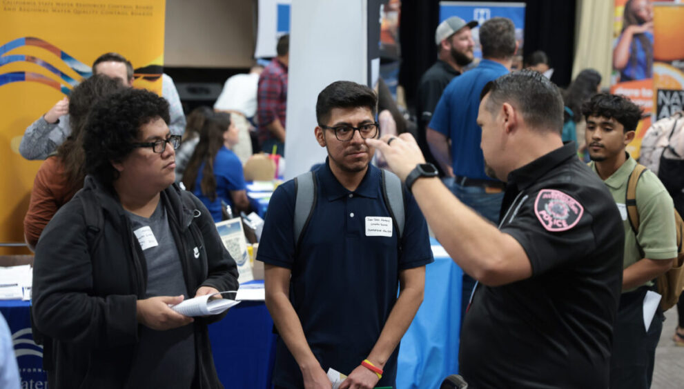 Computer science majors, Martinez and Marquez speak to a police officer representing one of the numerous companies and organizations at the 2023 Fall Career Fair.