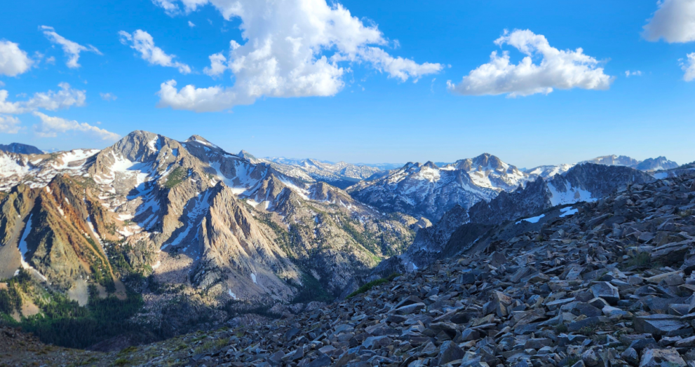 sierra nevada mountain range, mountains have a light dusting of snow and the sky is blue and full of white clouds