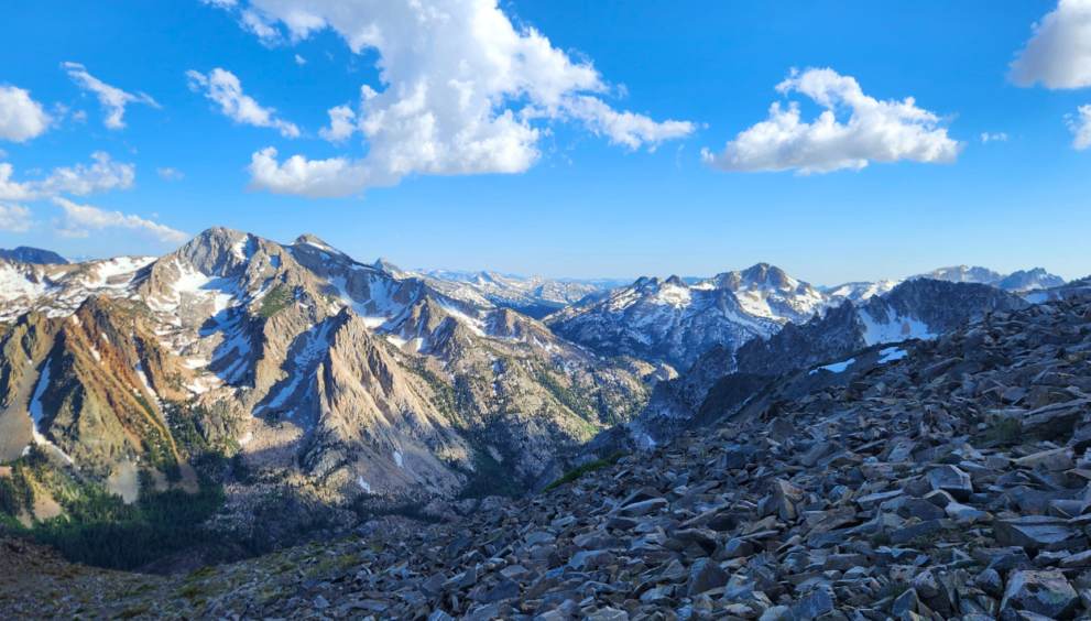 sierra nevada mountain range, mountains have a light dusting of snow and the sky is blue and full of white clouds