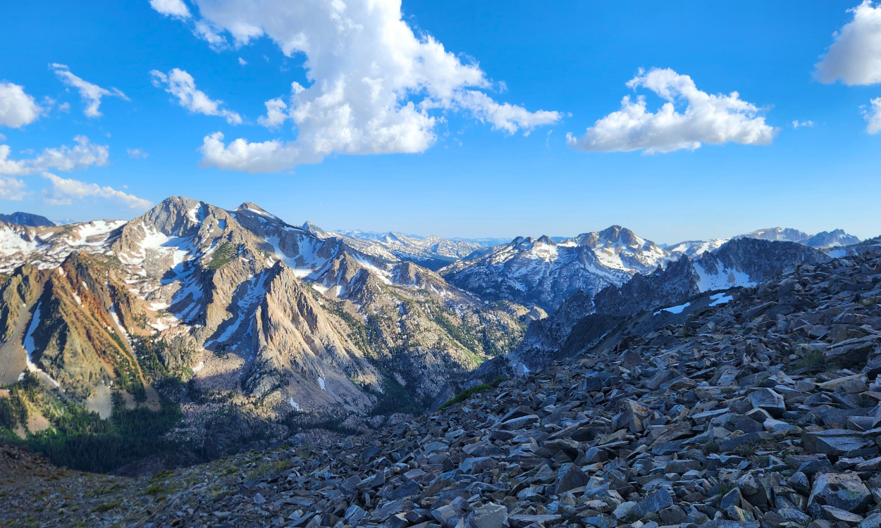 sierra nevada mountain range, mountains have a light dusting of snow and the sky is blue and full of white clouds